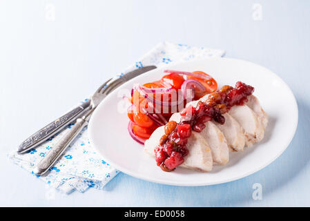 Filet de poulet avec une salade de tomates et relish de canneberges, fond bleu clair Banque D'Images