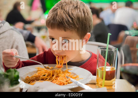 Garçon assis dans un restaurant mange du spaghetti Banque D'Images