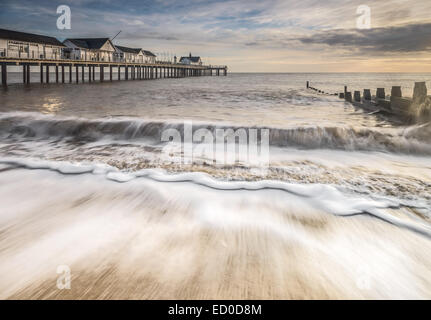 Lumière dorée sur Southwold Pier, montrant les vagues se brisant sur la plage en face. Banque D'Images