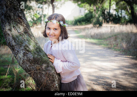 Fille souriante portant un bandeau floral appuyé contre un arbre, Andalousie, Espagne Banque D'Images