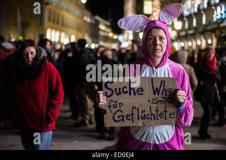 Munich, Allemagne. Dec 22, 2014. Une femme déguisée en bunny participe à une manifestation contre l'extrémisme de droite, la xénophobie, et le mouvement anti-Islam 'Pegida» à Munich, Allemagne, 22 décembre 2014. Elle est titulaire d'un panneau 'Suche Wohnung Zimmer für Geflüchtete" (lit. 'À la recherche appartement chambre pour les réfugiés). Photo : Nicolas Armer/dpa/Alamy Live News Banque D'Images