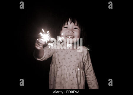 Girl holding sparkler outdoors Banque D'Images