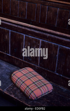 Rouge kneeler tartan décolorées ou brodé ou un coussin allongé sur le siège ou en bois foncé pew Banque D'Images