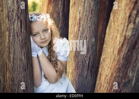 Première communion girl (8-9) leaning against tree Banque D'Images