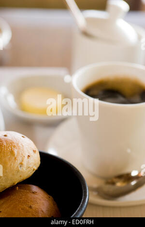 Les petits pains avec du beurre et du café noir sur la table Banque D'Images