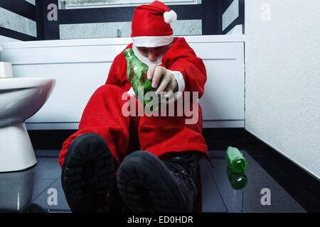 Drunken santa claus dormir à la salle de bains privative avec une bouteille de bière dans la main Banque D'Images
