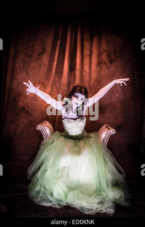 Fantasy makeover photographie : une jeune femme fille modèle fabriqué jusqu'à ressembler à une porcelaine peinte à face blanche marionnette et posant comme une poupée dans un studio de photo portant une robe verte robe de bal robe Banque D'Images
