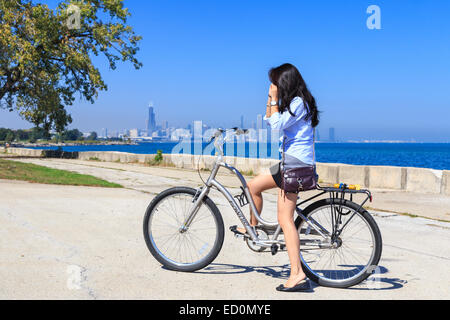 Fille sur son vélo avant de le lointain horizon de Chicago au lac Michigan. Banque D'Images