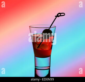 Peu de verre avec un liquide rouge et vert olive, rainbow background Banque D'Images