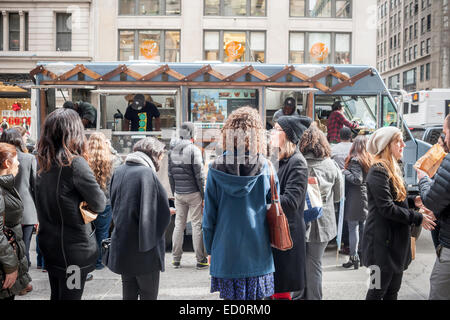 Des hordes d'amateurs queue à la Snowday chariot à New York le Mercredi, Décembre 17, 2014 pour célébrer la Journée nationale du sirop, le partenariat avec le sirop d'érable canadien, avec des échantillons gratuits de nombreux plats, y compris le sirop d'érable et au fromage de porc fumé-curseurs. Le camion alimentaire conscient socialement, partie de conduire le changement, exécute un programme utilisant l'anciennement incarcérées. (© Richard B. Levine) Banque D'Images