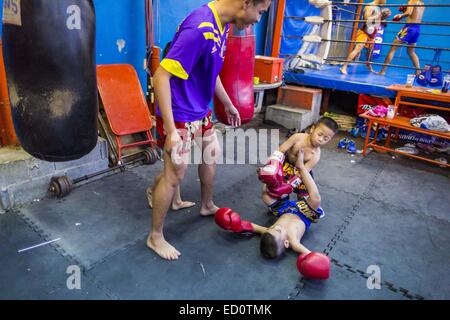 Bangkok, Bangkok, Thaïlande. Dec 23, 2014. Spar les garçons sur le sol dans la salle de sport Kanisorn à Bangkok. Le Kanisorn boxing gym est une petite salle de sport le long de la Wong Wian Yai - Samut Sakhon voie ferrée. Les jeunes des communautés voisines viennent à la salle de sport pour apprendre la boxe. Le Muay Thai (Muai thaï) est un art martial mixte développé en Thaïlande. Le Muay Thai est devenue très répandue dans le monde au xxe siècle, quand les boxeurs Thaï défait d'autres boxeurs bien connu. Une ligue professionnelle est régie par le monde Conseil de Muay Thai. Muay Thai est souvent considérée comme un moyen de sortir de la pauvreté des jeunes Thaïlandais. Le Muay Banque D'Images