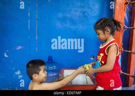 Bangkok, Bangkok, Thaïlande. Dec 23, 2014. Un garçon boxer mains une tasse d'eau à BAI THONG, 7 ans, après avoir travaillé à l'Kanisorn sport à Bangkok. Elle a été la boxe pour environ 5 mois. Le Kanisorn boxing gym est une petite salle de sport le long de la Wong Wian Yai - Samut Sakhon voie ferrée. Les jeunes des communautés voisines viennent à la salle de sport pour apprendre la boxe. Le Muay Thai (Muai thaï) est un art martial mixte développé en Thaïlande. Le Muay Thai est devenue très répandue dans le monde au xxe siècle, quand les boxeurs Thaï défait d'autres boxeurs bien connu. Une ligue professionnelle est régie par le Banque D'Images