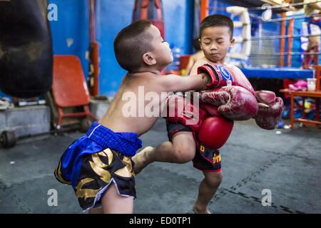 Bangkok, Bangkok, Thaïlande. Dec 23, 2014. Spar les garçons sur le sol dans la salle de sport Kanisorn à Bangkok. Le Kanisorn boxing gym est une petite salle de sport le long de la Wong Wian Yai - Samut Sakhon voie ferrée. Les jeunes des communautés voisines viennent à la salle de sport pour apprendre la boxe. Le Muay Thai (Muai thaï) est un art martial mixte développé en Thaïlande. Le Muay Thai est devenue très répandue dans le monde au xxe siècle, quand les boxeurs Thaï défait d'autres boxeurs bien connu. Une ligue professionnelle est régie par le monde Conseil de Muay Thai. Muay Thai est souvent considérée comme un moyen de sortir de la pauvreté des jeunes Thaïlandais. Le Muay Banque D'Images