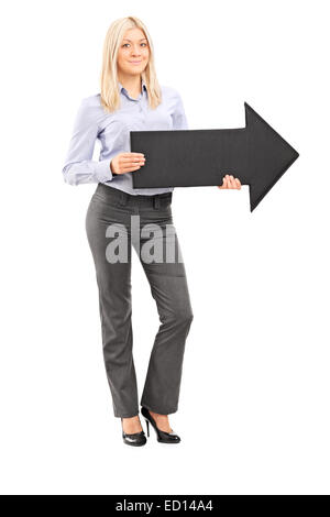 Full Length portrait of a smiling woman holding blonde une grosse flèche noire pointant vers la droite isolé sur fond blanc Banque D'Images