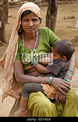 Femme d'une tribu Adivasi allaiter son enfant au village près de Poshina, Gujarat, Inde Banque D'Images