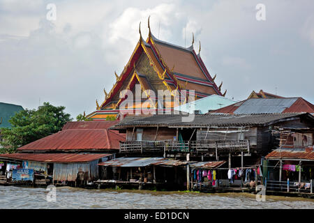 Thaïlande - Blanchisserie étendus dehors des baraques le long de la Choa Phraya et un temple richement décoré au-delà de Bangkok. Banque D'Images