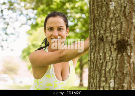 Happy fit brunette stretching contre un arbre Banque D'Images