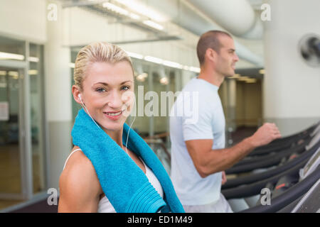 Fit young couple running sur des tapis roulants at gym Banque D'Images