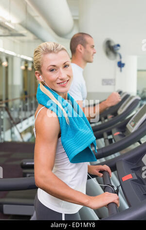 Fit young couple running sur des tapis roulants at gym Banque D'Images