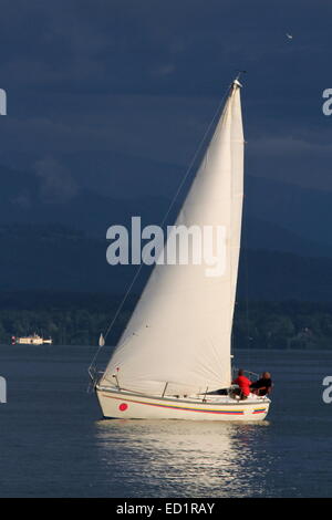White voilier naviguant sur une soirée calme avec orange, le lac de Genève, Suisse Banque D'Images