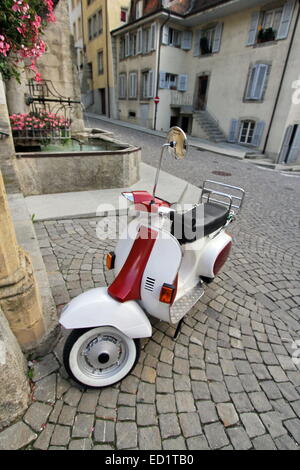 Rouge et blanc classique scooter stationné dans la vieille rue étroite d'Estavayer-le-Lac, canton de Fribourg, Suisse Banque D'Images