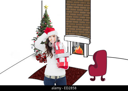 Composite image of brunnette in santa hat holding gifts Banque D'Images