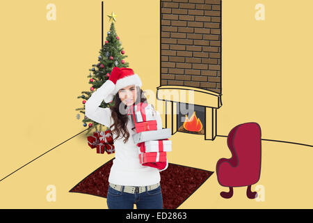 Composite image of brunnette in santa hat holding gifts Banque D'Images