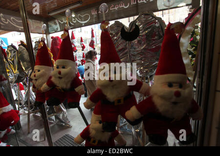 La ville de Gaza, bande de Gaza, territoire palestinien. Le 24 décembre, 2014. Une femme palestinienne passe devant une boutique décorée avec des jouets du père Noël, pour célébrer les vacances de Noël dans la ville de Gaza le 24 décembre 2014 Crédit : Ashraf Amra/APA/Images/fil ZUMA Alamy Live News Banque D'Images