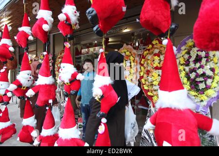 La ville de Gaza, bande de Gaza, territoire palestinien. Le 24 décembre, 2014. Une femme palestinienne passe devant une boutique décorée avec des jouets du père Noël, pour célébrer les vacances de Noël dans la ville de Gaza le 24 décembre 2014 Crédit : Ashraf Amra/APA/Images/fil ZUMA Alamy Live News Banque D'Images