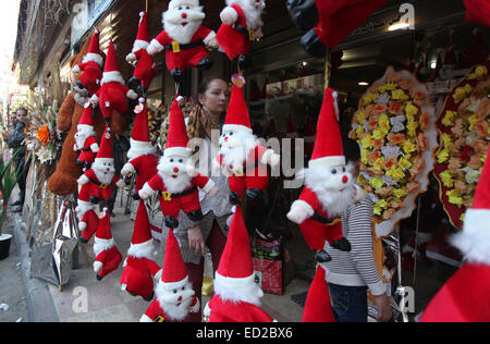 La ville de Gaza, bande de Gaza, territoire palestinien. Le 24 décembre, 2014. Une femme palestinienne passe devant une boutique décorée avec des jouets du père Noël, pour célébrer les vacances de Noël dans la ville de Gaza le 24 décembre 2014 Crédit : Ashraf Amra/APA/Images/fil ZUMA Alamy Live News Banque D'Images