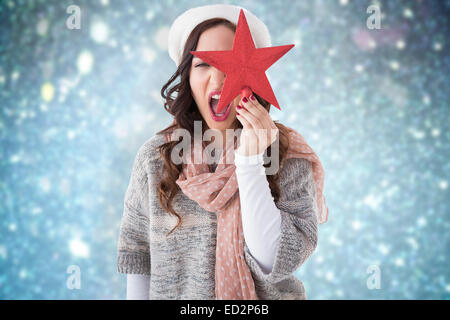 Image composite de brunette in winter clothes holding star Banque D'Images