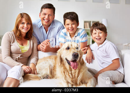 Les garçons mignons, leurs parents et le chien se reposer sur un canapé à la maison Banque D'Images