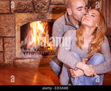 Portrait de couple doux assis près de cheminée et s'embrasser sur station de ski de luxe, romantique célébration de la Saint-Valentin Banque D'Images