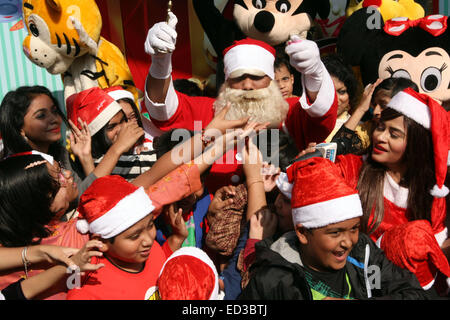 Le Père Noël pose avec les enfants du Bangladesh pour les photos pendant une fête de Noël à Dhaka le 25 décembre 2014. Banque D'Images