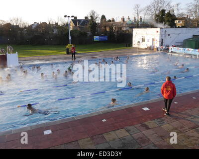 Londres, Royaume-Uni. 25 Décembre, 2014. Les nageurs prennent à Hampton piscine de plein air, Middlesex, par un froid matin de Noël claire. L'eau de piscine chaude crée un brouillard. Cet événement se produit chaque Noël et est une occasion conviviale et ludique pour tous les âges. Crédit : Charles Bowman/Alamy Live News Banque D'Images