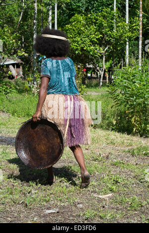 En Mélanésie, la Papouasie-Nouvelle-Guinée, l'île de Dobu. Femme en jupe d'herbe avec plaque en bois. Banque D'Images