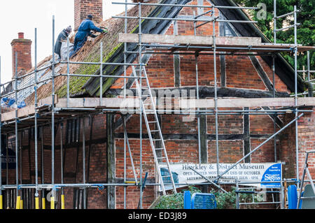 Deux hommes travaillant à remplacer le toit de chaume de l'Hinckley and District Museum building Banque D'Images