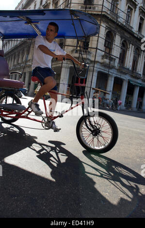 La HAVANE, CUBA - 18 MAI 2011 : les lecteurs de vélo taxi cubain classique architecture coloniale passée dans le centre de La Havane. Banque D'Images