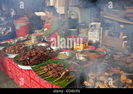 La cuisson et la vente d'aliments femme au marché en plein air de Luang Prabang, Laos Banque D'Images