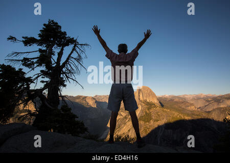 Un touriste sur Glacier Point donnant sur le demi-dôme et la vallée de Yosemite, California, USA. Banque D'Images