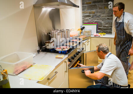 Deux hommes chefs préparer préparer un repas dans une cuisine moderne, UK Banque D'Images