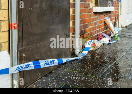 Belfast, Irlande du Nord. 27 déc 2014 - bande de la police se trouve sur l'extérieur de fleurs une maison où un meurtre a eu lieu Crédit : Stephen Barnes/Alamy Live News Banque D'Images