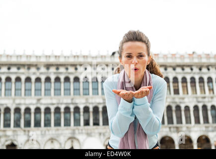 Young woman blowing kiss sur la piazza San Marco à Venise, Italie Banque D'Images