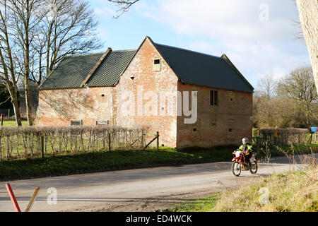 La plaine de Salisbury, Wiltshire, UK, le 27 décembre 2014. Un motard passe l'un des cottages dans le village. Communément appelé Le Bell Inn. Imber village a été évacué, il y a 70 ans par l'armée en 1943 en préparation d'DDay et demeure aujourd'hui déserte. Au cours de la période de Noël Le ministère de la défense permet aux visiteurs de la commune les jours fériés. Credit : Wayne Farrell/Alamy Live News Banque D'Images