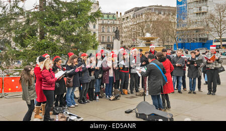 TRAFALGAR SQUARE LONDRES, MEMBRES D'UN CHŒUR chantant des chants de Noël SOUS L'ARBRE DE NOËL Banque D'Images