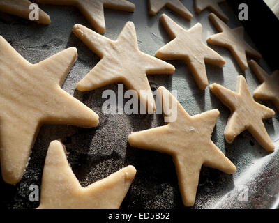 Pâte crue biscuits de Noël en forme d'étoiles sur une plaque de cuisson prêt à aller dans le four de Galles UK KATHY DEWITT Banque D'Images