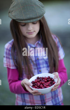 Girl holding freshly picked les canneberges dans un bol blanc. Banque D'Images