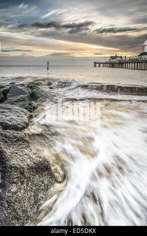 Lever de soleil sur Southwold Peir, montrant les vagues se brisant sur la plage en face, prise comme un portrait de l'image. Banque D'Images