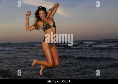 Femme en costume de bain sautant sur beach Banque D'Images