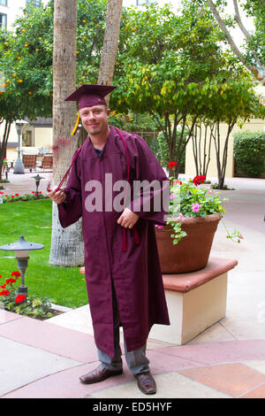 Diplômé de l'université d'âge mûr en cap and gown heureusement twirling glands Banque D'Images